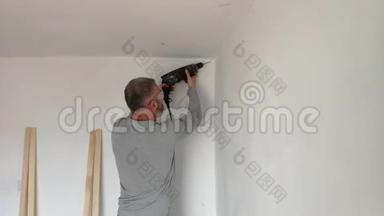 一个人钻白色的墙，钻，混凝土，电钻，关闭手握电钻在白色的房间。